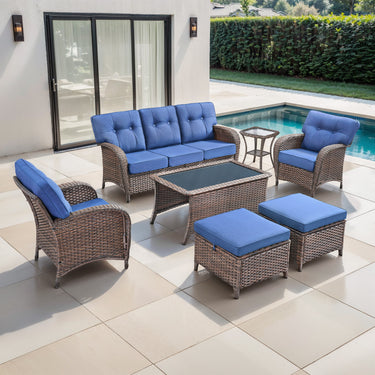 Belord 7-piece patio conversation set with brown wicker, blue cushions, including sofa, chairs, tables, and footstools.