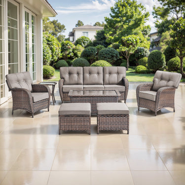 Belord 7-piece patio conversation set with brown wicker, grey cushions, includes sofa, chairs, tables, and footstools.